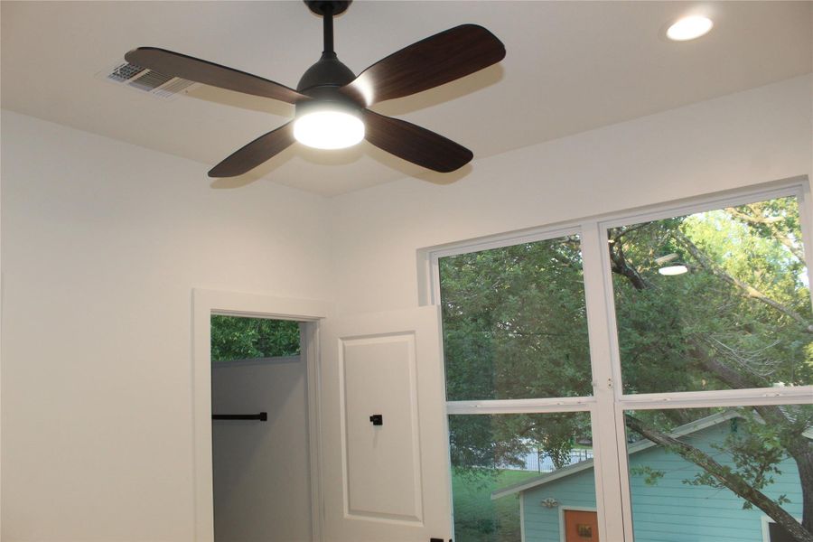 A quiet bedroom offers outdoor views and a ceiling fan for comfortable living.