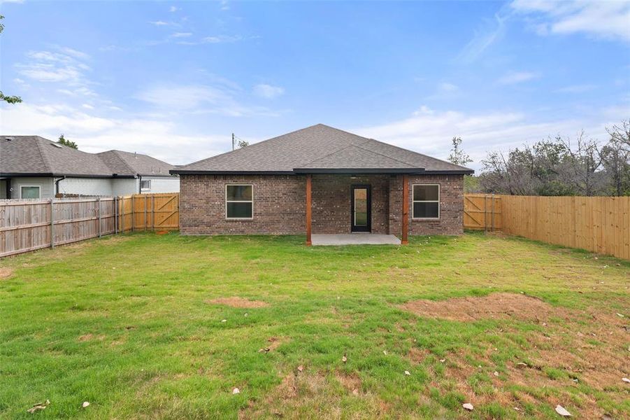 Rear view of house with a patio, brick siding, a fenced backyard, and a shingled roof