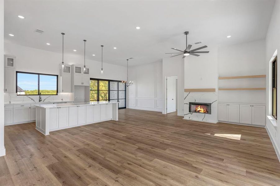 Kitchen with glass insert cabinets, white cabinets, a spacious island, recessed lighting, and light wood-style flooring