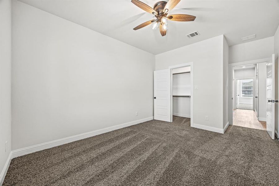 Unfurnished bedroom featuring a closet, dark colored carpet, and ceiling fan