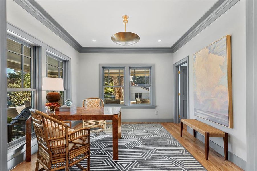 Office area with ornamental molding and light hardwood / wood-style flooring