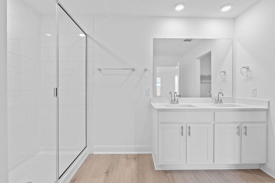 Bathroom featuring light wood-style flooring, double vanity, a shower stall, and recessed lighting Bathroom featuring light wood-style flooring, double vanity, a shower stall, and recessed lighting