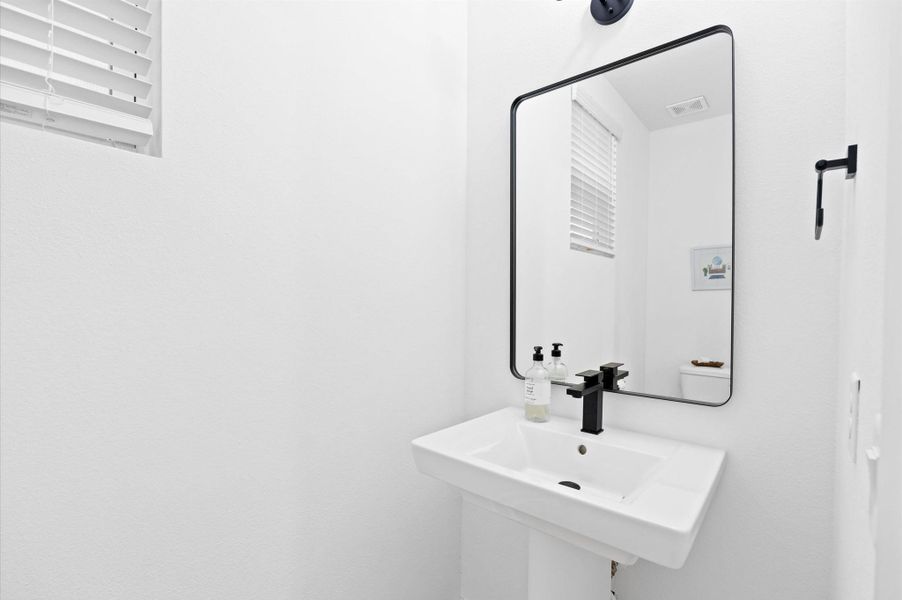 A stylish and functional powder room located on the first floor, perfect for guests. The space features elegant finishes, such as a modern pedestal sink, sleek fixtures, and tasteful lighting that enhances its inviting atmosphere. A stylish and functional powder room located on the first floor, perfect for guests. The space features elegant finishes, such as a modern pedestal sink, sleek fixtures, and tasteful lighting that enhances its inviting atmosphere.