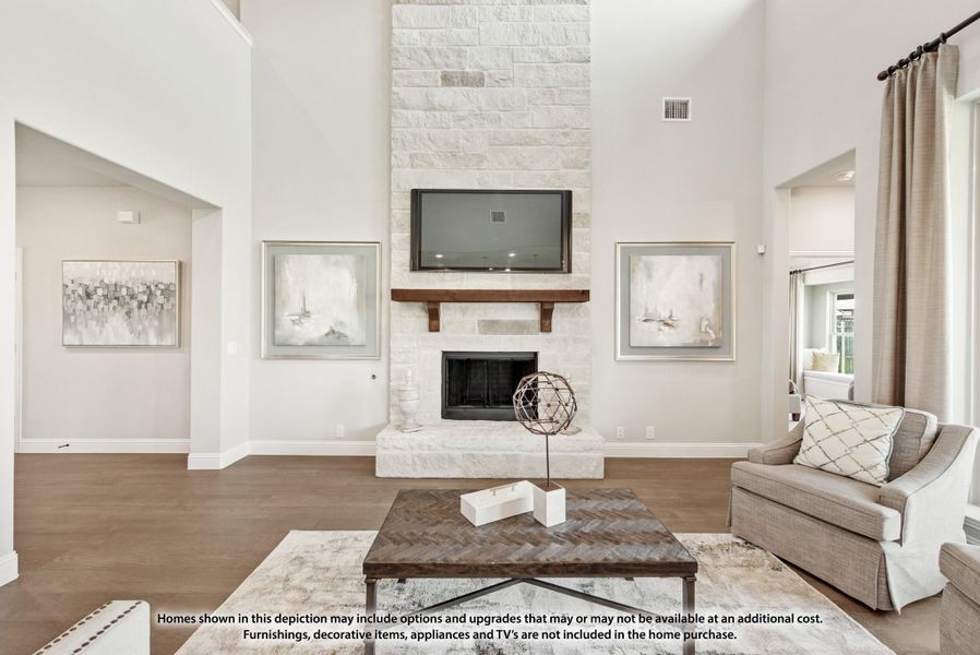 Living room with floor-to-ceiling stone fireplace, wood mantel, wall-mounted TV, and high ceilings with hardwood floors Living room with floor-to-ceiling stone fireplace, wood mantel, wall-mounted TV, and high ceilings with hardwood floors