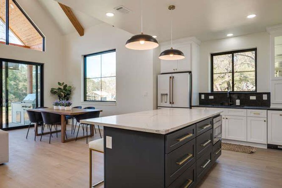 Kitchen featuring white cabinets, a center island, pendant lighting, high end white fridge, and recessed lighting
