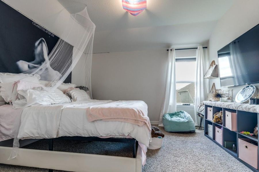 A large window allows natural light to brighten the space, complemented by a wall-mounted TV and organized shelving for storage.