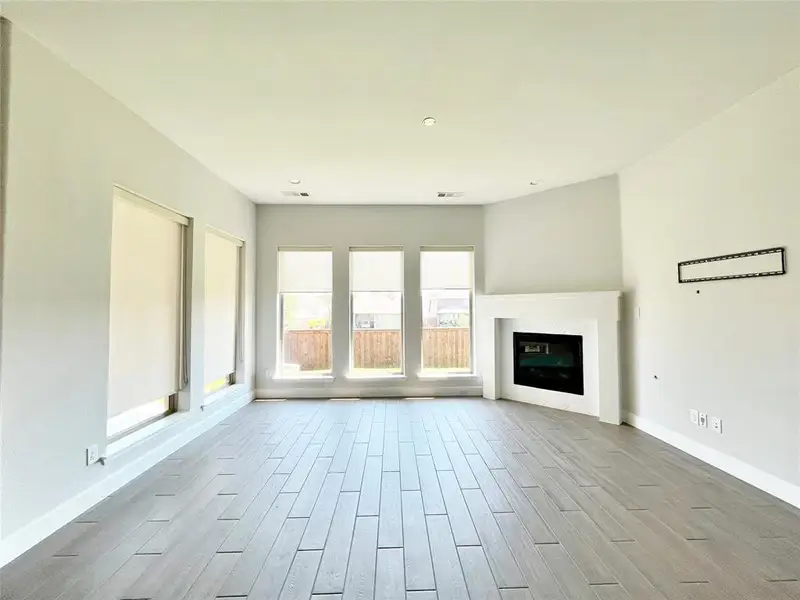 Unfurnished living room with wood finish floors and a glass covered fireplace Unfurnished living room with wood finish floors and a glass covered fireplace
