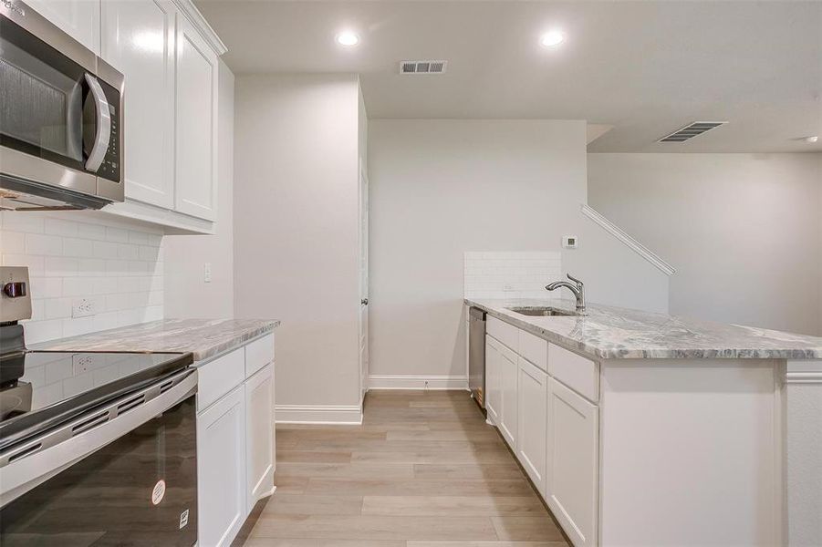 Kitchen featuring appliances with stainless steel finishes, backsplash, white cabinetry, and recessed lighting Kitchen featuring appliances with stainless steel finishes, backsplash, white cabinetry, and recessed lighting