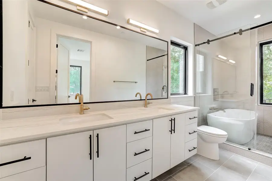 Bathroom with double vanity, a freestanding bath, tile patterned floors, and a shower stall