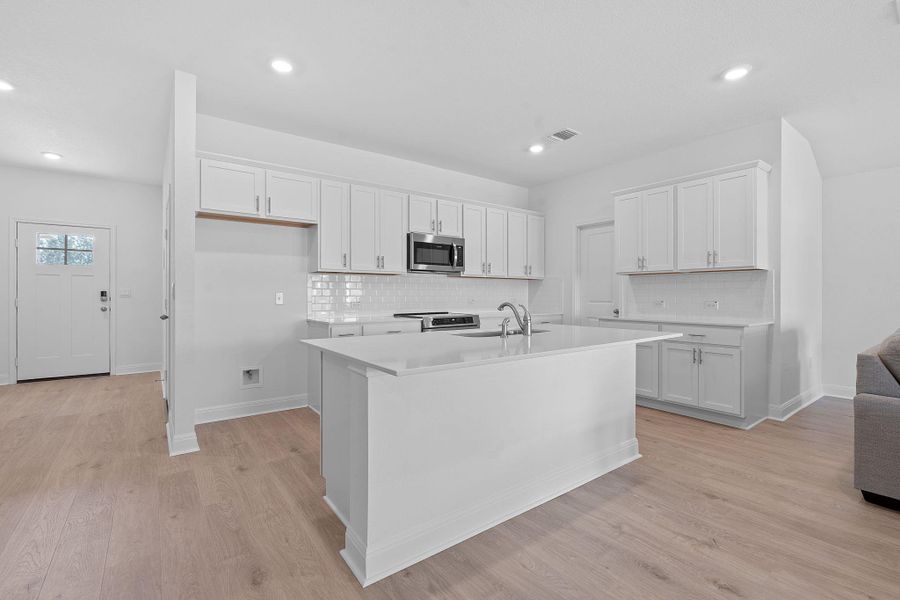 Kitchen with tasteful backsplash, white cabinets, stainless steel appliances, light wood-type flooring, and recessed lighting Kitchen with tasteful backsplash, white cabinets, stainless steel appliances, light wood-type flooring, and recessed lighting