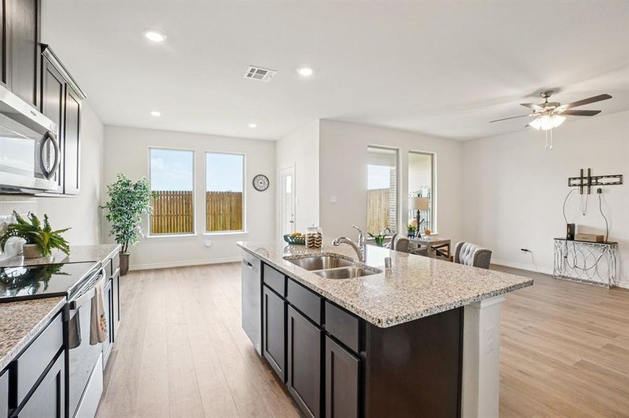 Kitchen featuring appliances with stainless steel finishes, light stone counters, light wood finished floors, ceiling fan, and recessed lighting Kitchen featuring appliances with stainless steel finishes, light stone counters, light wood finished floors, ceiling fan, and recessed lighting