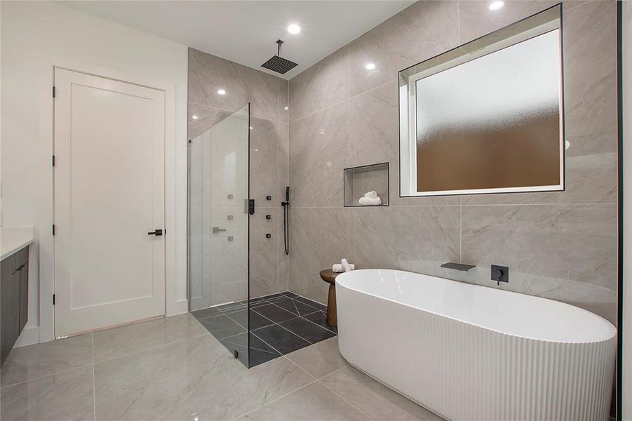 Bathroom featuring tile walls and independent shower and bath