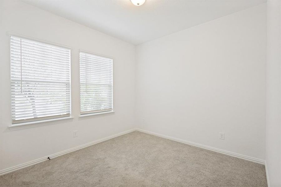 Room featuring two windows with horizontal blinds, neutral-toned carpeting, white walls, and a ceiling-mounted light fixture