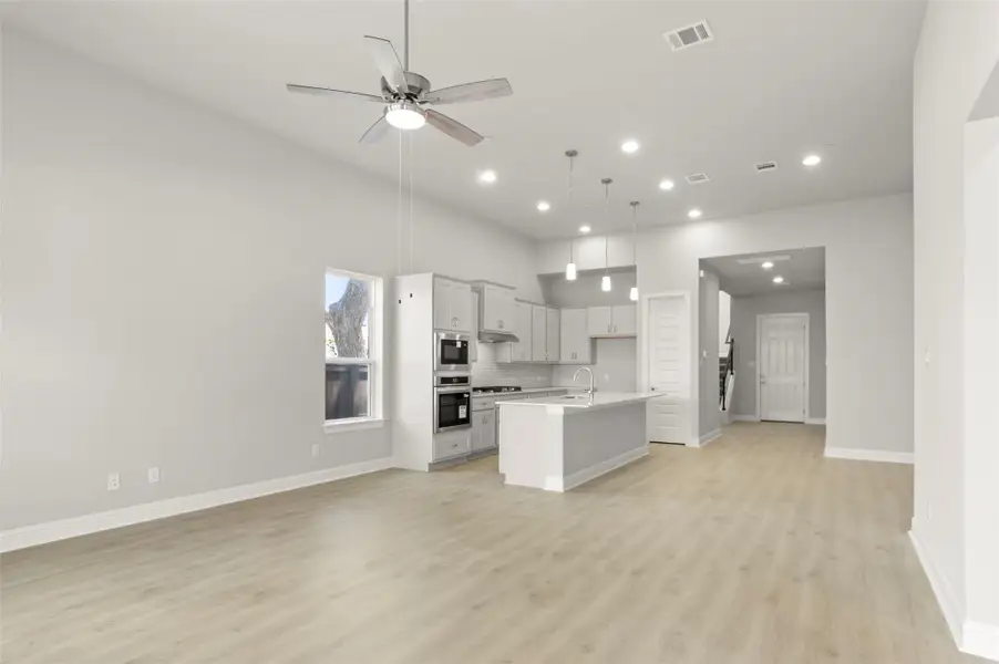 Kitchen with open floor plan, light wood-style flooring, a kitchen island with sink, recessed lighting, and backsplash Kitchen with open floor plan, light wood-style flooring, a kitchen island with sink, recessed lighting, and backsplash