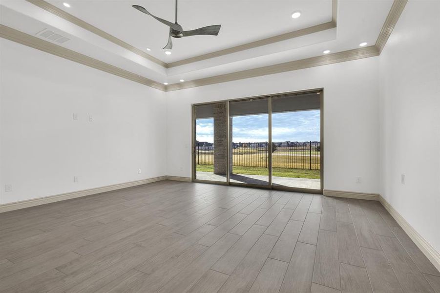 Spare room with a raised ceiling, light wood-style floors, ceiling fan, recessed lighting, and ornamental molding