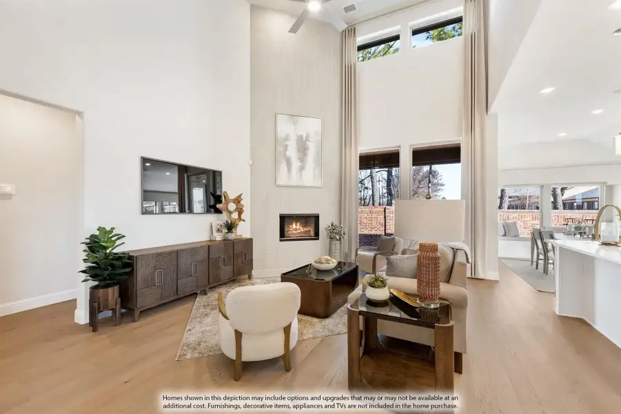 Living room with two-story ceiling, tile fireplace, hardwood floors, and large windows