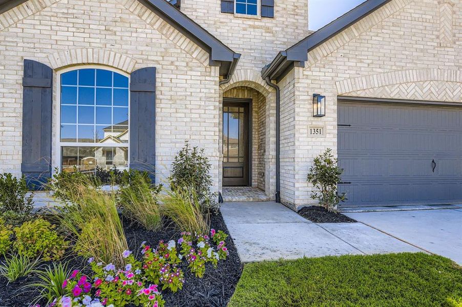 Entrance to property featuring brick siding, driveway, a garage, and stone siding Entrance to property featuring brick siding, driveway, a garage, and stone siding