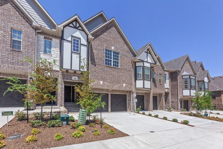 Tudor home featuring concrete driveway, an attached garage, a residential view, and brick siding Tudor home featuring concrete driveway, an attached garage, a residential view, and brick siding