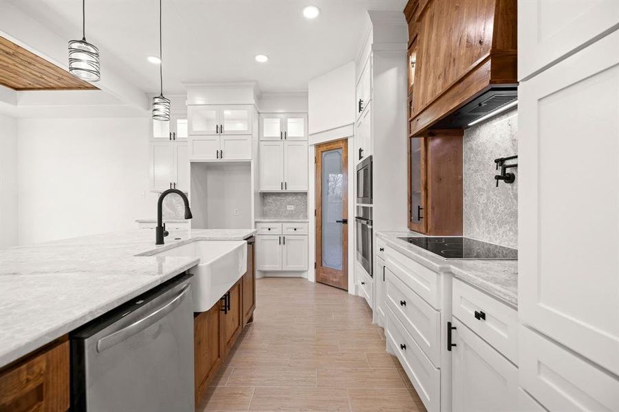 Kitchen featuring stainless steel appliances, tasteful backsplash, glass insert cabinets, a sink, and light stone countertops