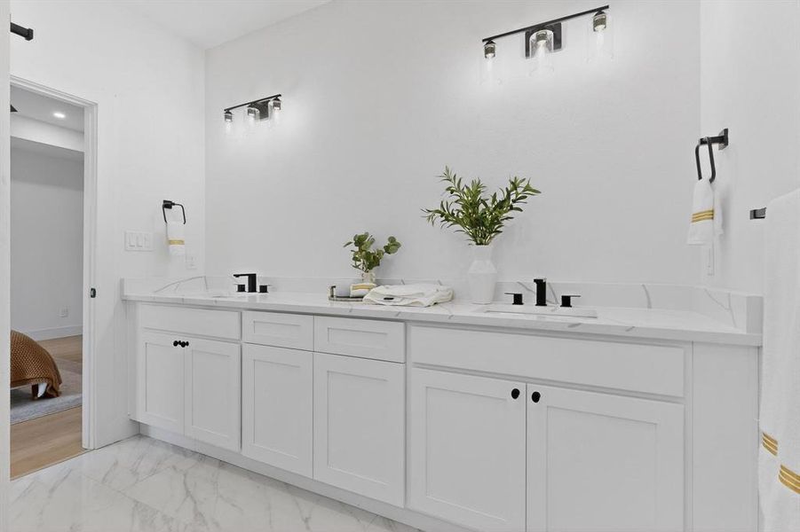 Full bathroom featuring double vanity and light marble finish floors