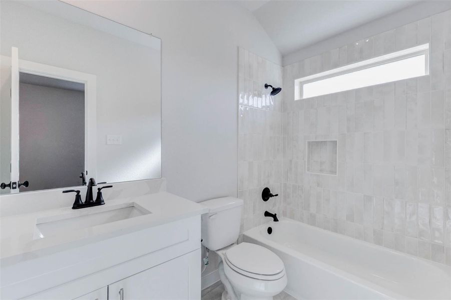 Beautifully designed shared bath with bright white cabinetry, sleek quartz vanity, and designer matte black fixtures. The shower/tub combo is accented with vertical tile and a picture window for both privacy and light.