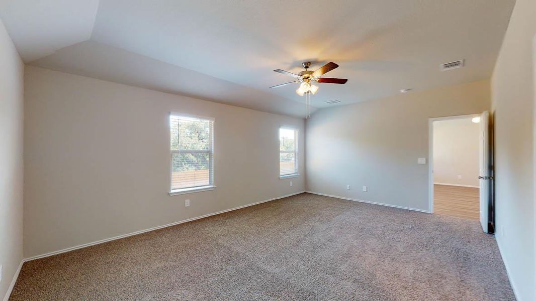 Empty room featuring light carpet, lofted ceiling, and a ceiling fan
