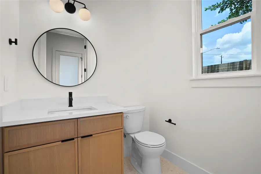 A well-lit powder room featuring a sleek vanity and a contemporary mirror.