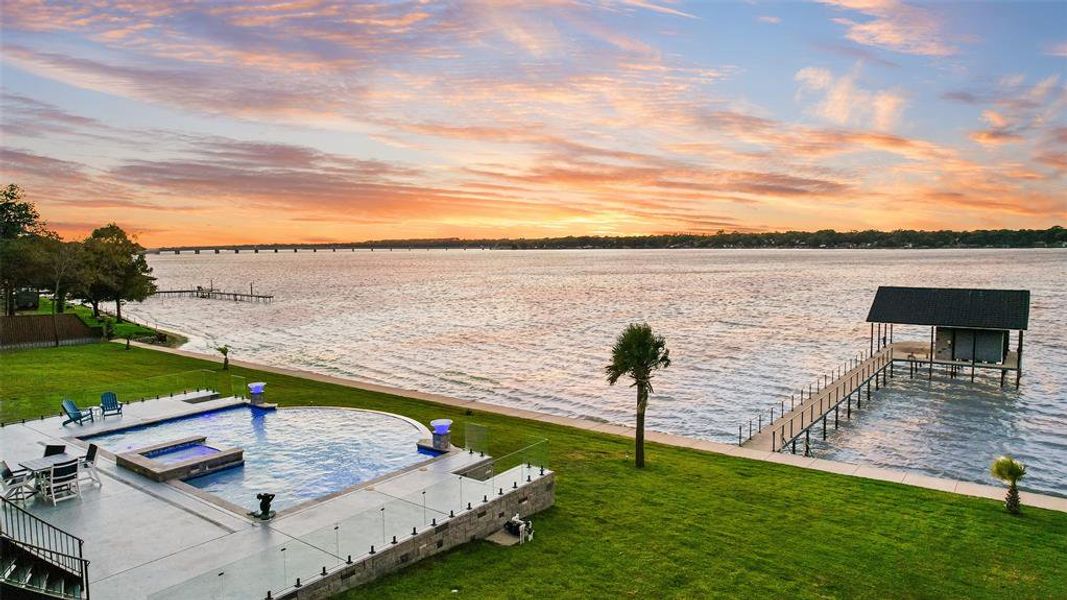 Dock featuring a water view, a lawn, a pool with connected hot tub, and a patio area Dock featuring a water view, a lawn, a pool with connected hot tub, and a patio area