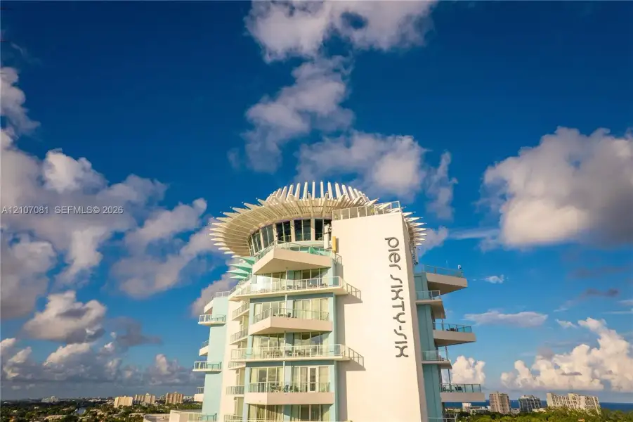 High-rise exterior featuring multi-level wraparound balconies, expansive glass sliding doors, and a distinct crown architectural detail High-rise exterior featuring multi-level wraparound balconies, expansive glass sliding doors, and a distinct crown architectural detail