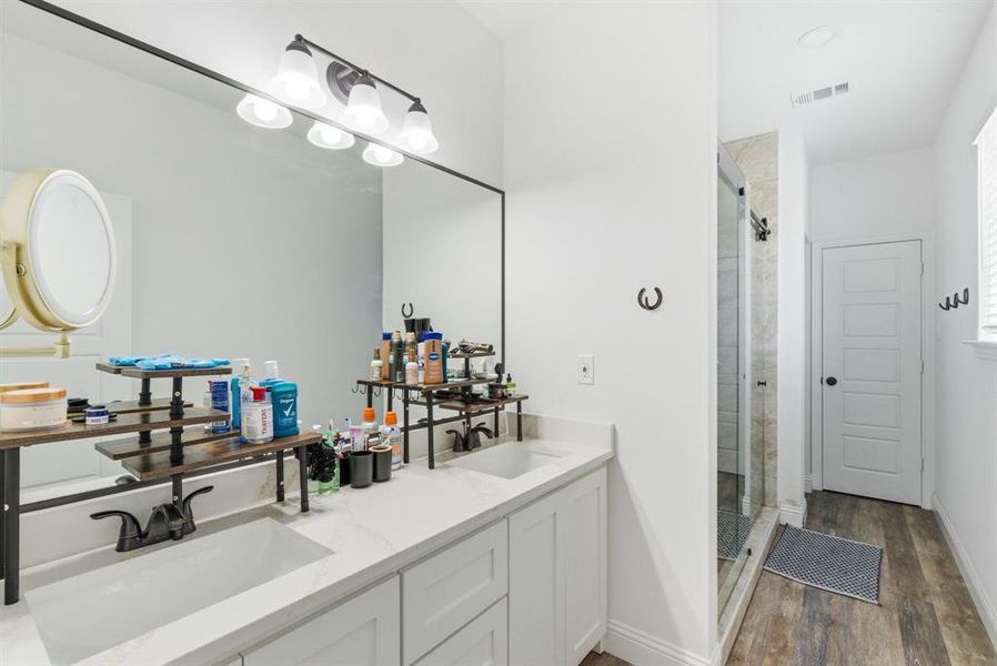 Full bathroom with double vanity, a stall shower, and dark wood finished floors Full bathroom with double vanity, a stall shower, and dark wood finished floors