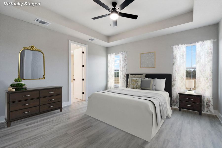 Bedroom with a raised ceiling, light wood-style floors, and a ceiling fan