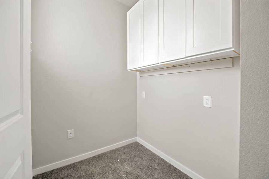 White shaker cabinetry provides essential storage options above the plush carpeting.