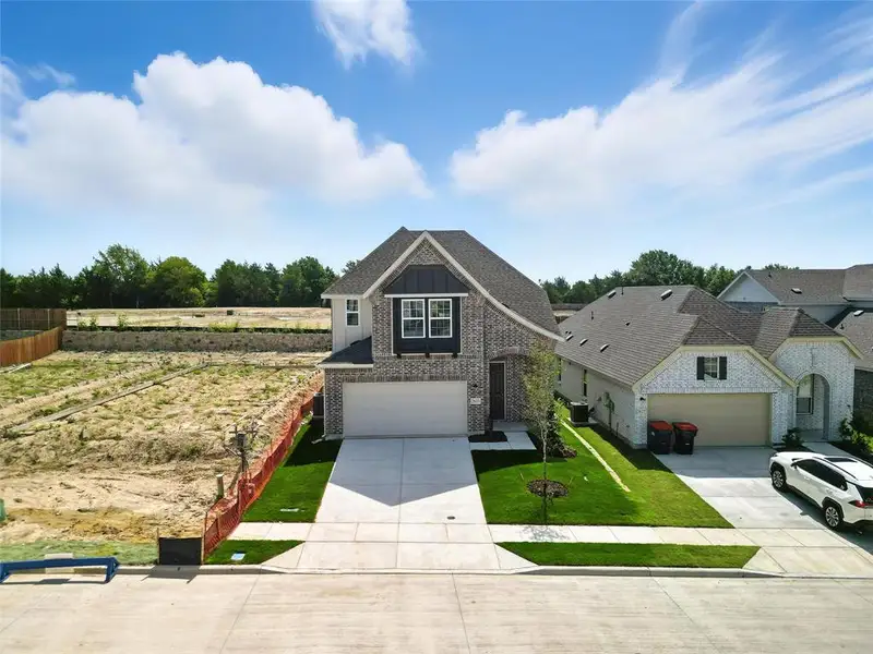 View of front of home featuring concrete driveway, brick siding, board and batten siding, and an attached garage View of front of home featuring concrete driveway, brick siding, board and batten siding, and an attached garage