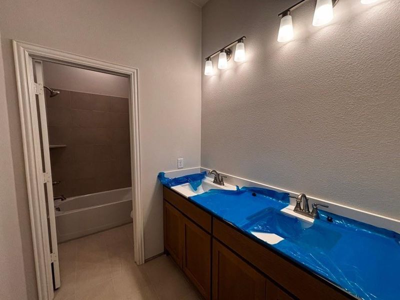 Bathroom vanity featuring a double sink with protected basins, brush nickel faucets, and a white countertop