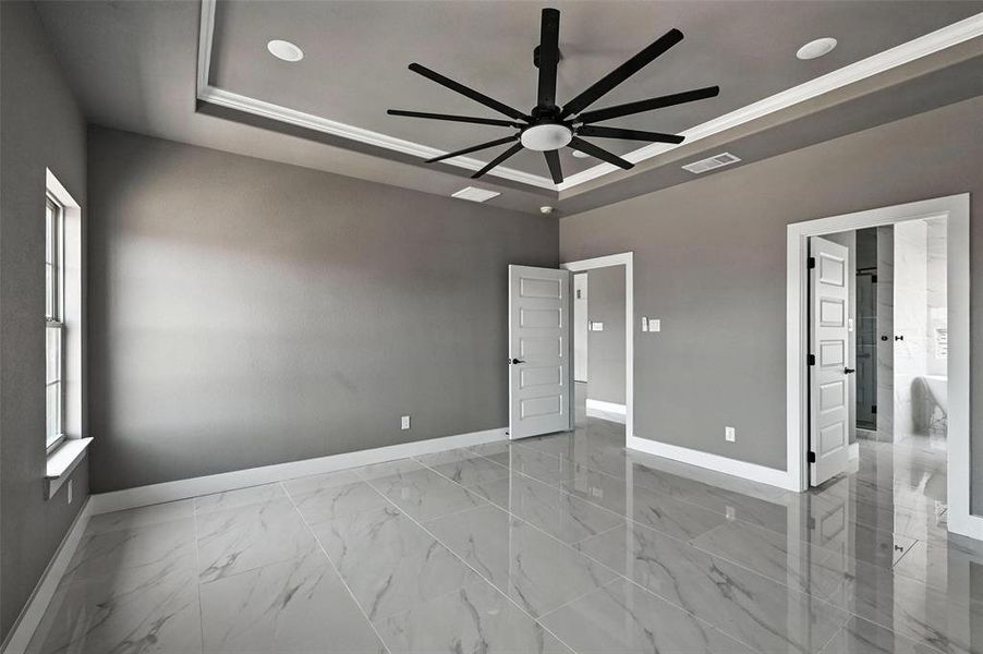 Empty room with a ceiling fan, marble look tile flooring, a tray ceiling, and recessed lighting Empty room with a ceiling fan, marble look tile flooring, a tray ceiling, and recessed lighting