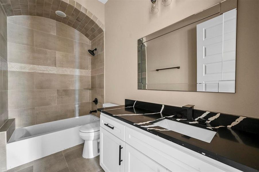 Full bathroom with tile patterned flooring, toilet, vanity, and tiled shower / bath