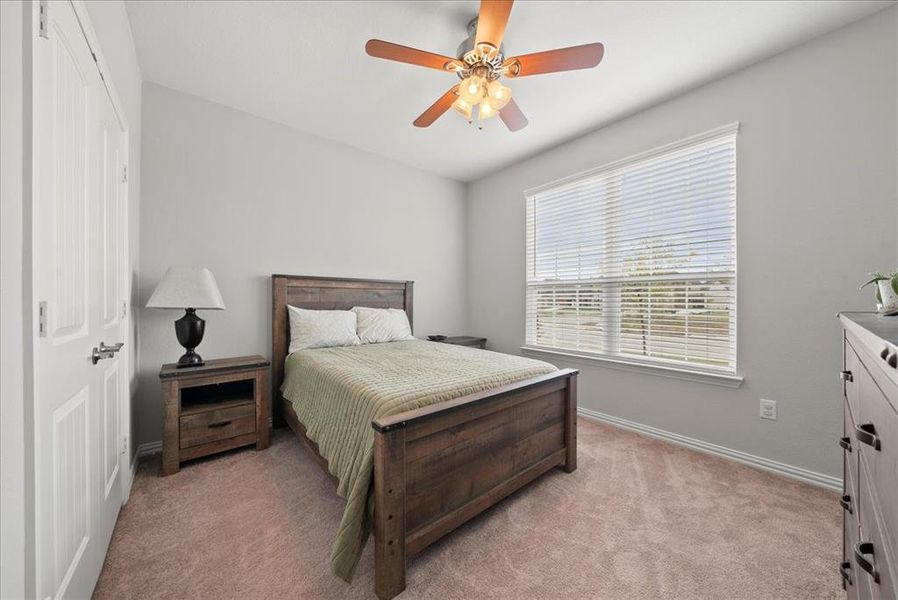 Bedroom 1 (downstairs) with closet, ceiling fan and light carpet.