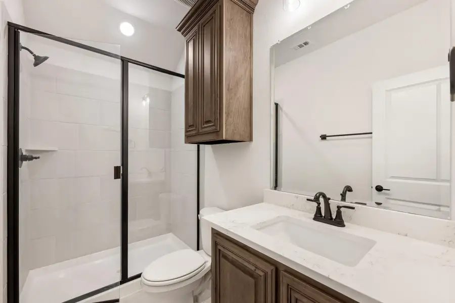 Bathroom with glass walk-in shower, dark wood vanity, quartz countertop, and black fixtures Bathroom with glass walk-in shower, dark wood vanity, quartz countertop, and black fixtures