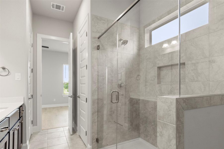 Bathroom with plenty of natural light, a shower stall, vanity, and tile patterned floors