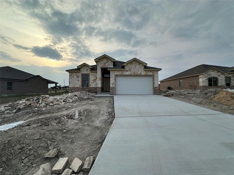 View of front of home with concrete driveway, stone siding, and a garage