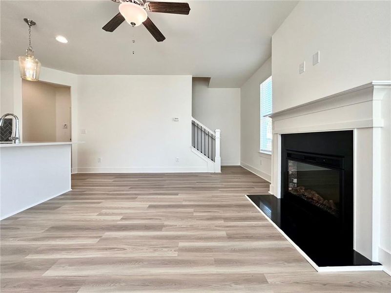 Unfurnished living room featuring sink, light wood-type flooring, and ceiling fan