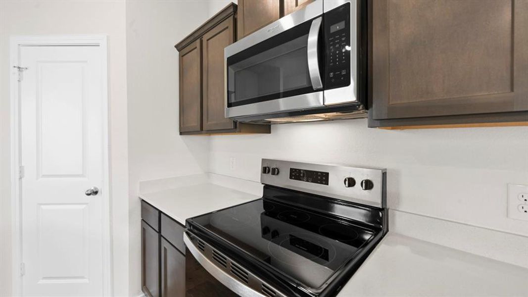 Kitchen featuring stainless steel appliances and dark wood finish cabinets