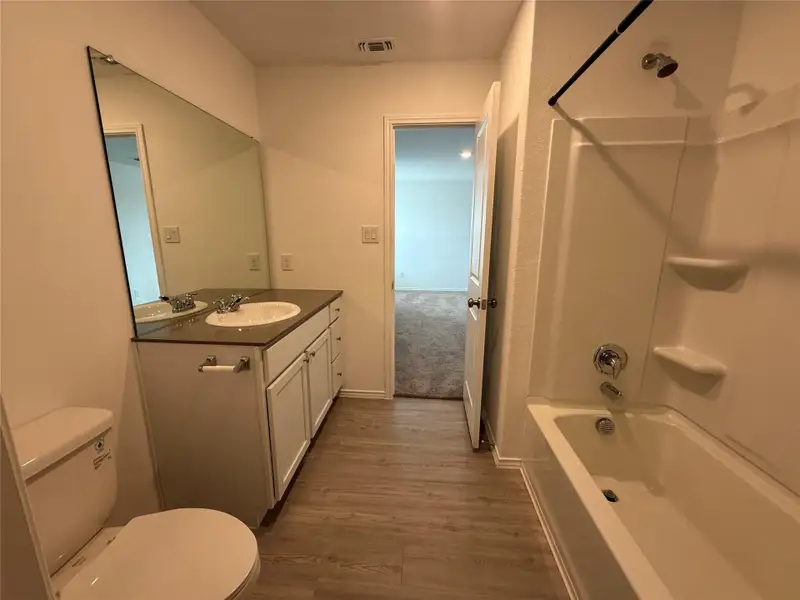 Full bathroom featuring tub / shower combination, vanity, and dark wood-type flooring
