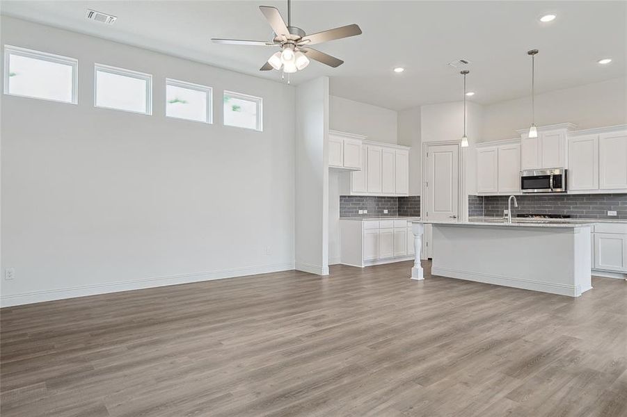 Kitchen with light hardwood / wood-style floors, ceiling fan, and white cabinets