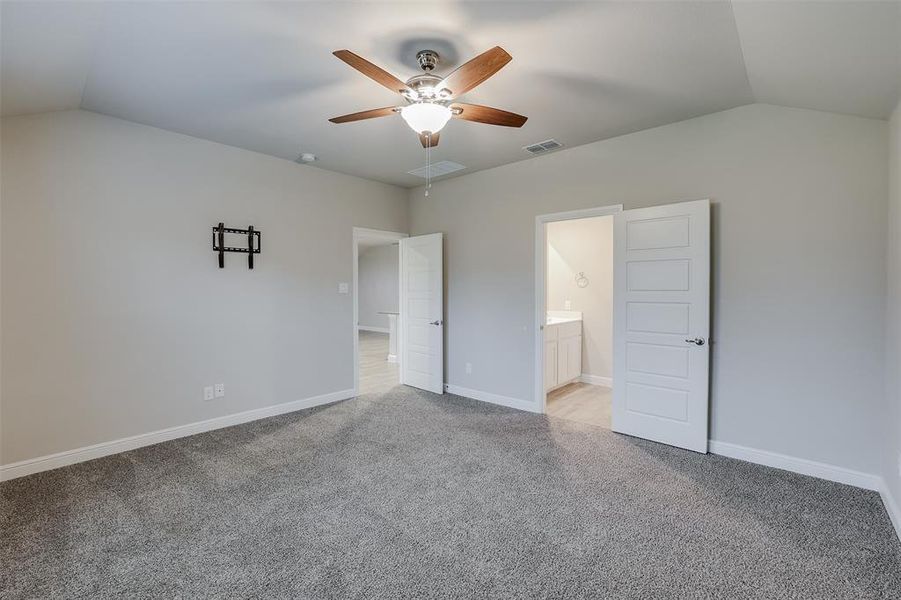 Unfurnished bedroom featuring vaulted ceiling, light colored carpet, ensuite bathroom, and ceiling fan Unfurnished bedroom featuring vaulted ceiling, light colored carpet, ensuite bathroom, and ceiling fan