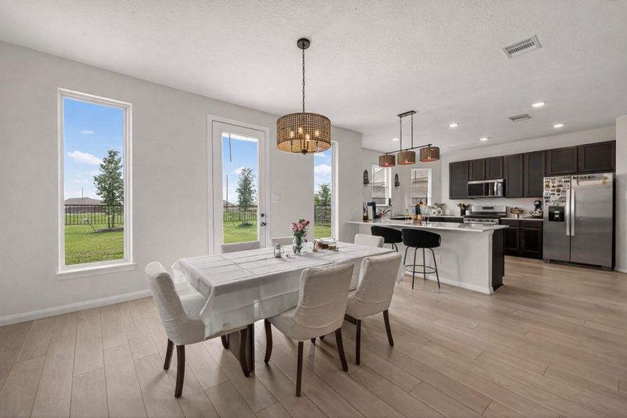 Light-filled dining area flows into U-shaped kitchen with quartz-look counters and oversized breakfast bar.