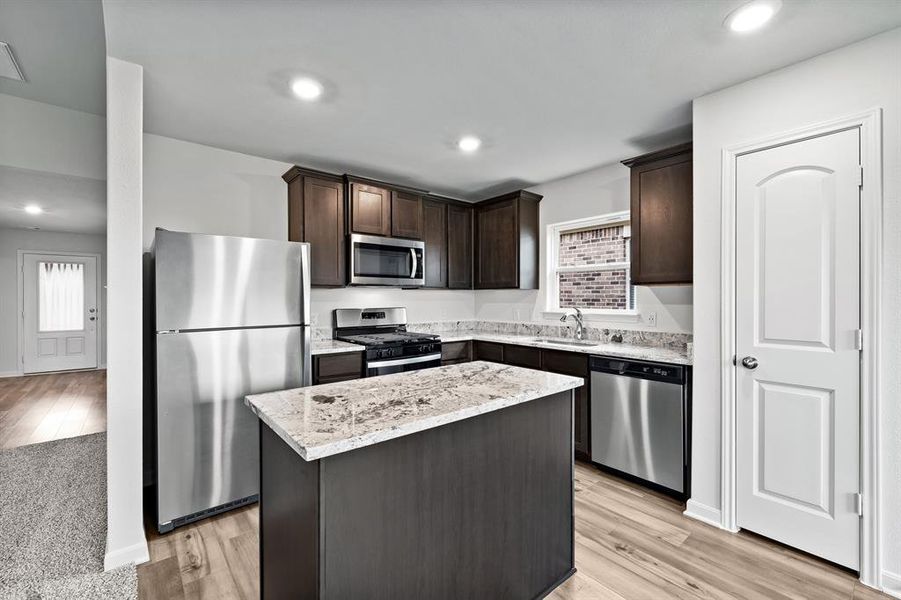 Kitchen featuring stainless steel appliances, a kitchen island, and light wood-type flooring