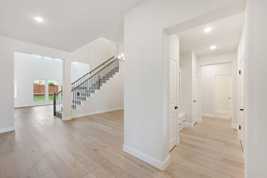Open foyer with staircase, light hardwood floors, white walls, and hallway leading to multiple rooms Open foyer with staircase, light hardwood floors, white walls, and hallway leading to multiple rooms