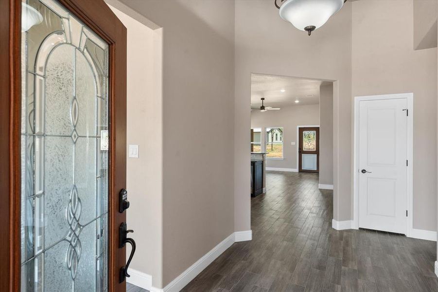 Entryway featuring a wood-finish door with decorative glass, wood-finish tile flooring, recessed lighting, and a neutral wall color