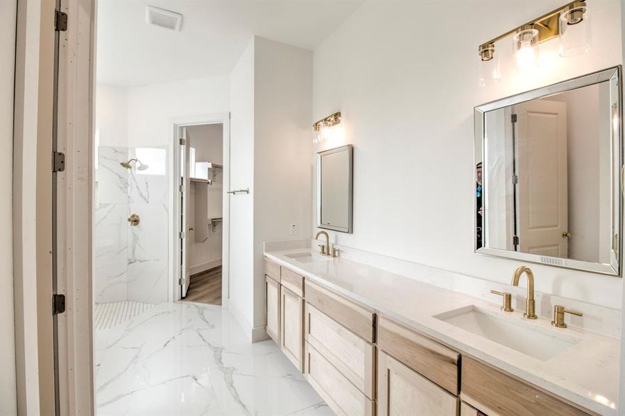 Full bath featuring a marble finish shower, double vanity, light marble finish floors, and a spacious closet Full bath featuring a marble finish shower, double vanity, light marble finish floors, and a spacious closet